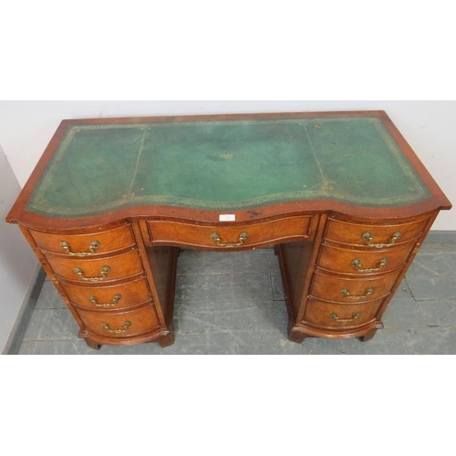 745 - An antique style walnut serpentine front kneehole desk with inset green leather writing surface, hou... 