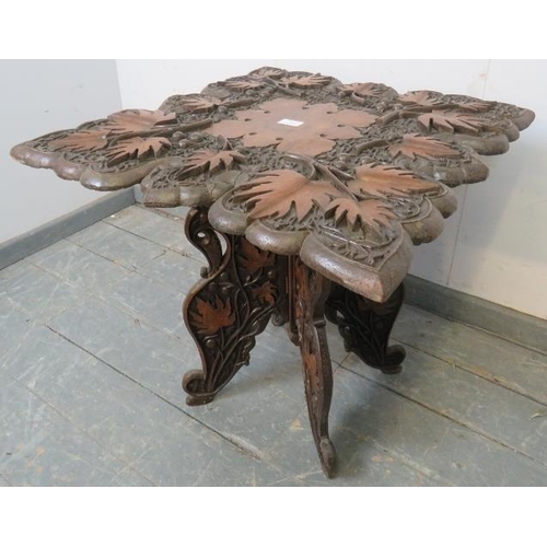 764 - An early 20th century Anglo Indian folding table, the shaped top with high relief carving depicting ... 