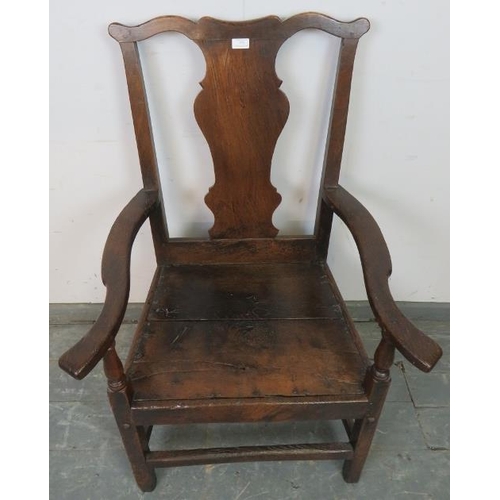 775 - An early 18th century oak elbow chair in the Queen Anne taste, with shaped back splat, on square sup... 