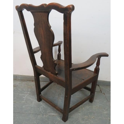 775 - An early 18th century oak elbow chair in the Queen Anne taste, with shaped back splat, on square sup... 