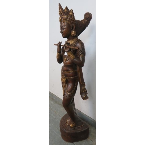 832 - A carved hardwood statue with gold accents depicting a Hindu goddess playing the flute. 
H117 W30 D2... 