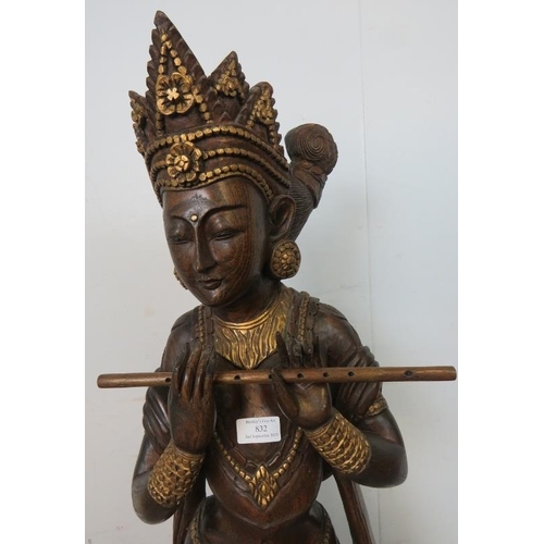 832 - A carved hardwood statue with gold accents depicting a Hindu goddess playing the flute. 
H117 W30 D2... 