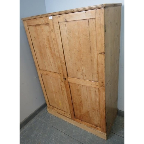 852 - An antique stripped pine narrow pantry cupboard, the panelled doors opening onto three loose shelves... 