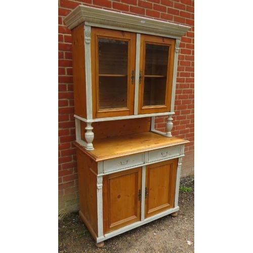 854 - An antique Continental pine kitchen dresser, the top section with carved cornice above glazed doors,... 