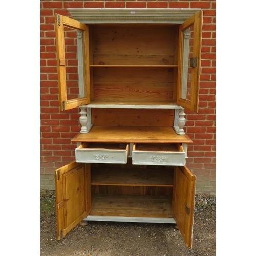 854 - An antique Continental pine kitchen dresser, the top section with carved cornice above glazed doors,... 