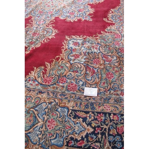 902 - A mid 20th century Persian carpet with a large central floral motif on a red ground with deep 52cm b... 