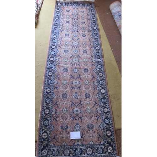 903 - A late 20th century Persian runner, central repeat pattern on dusky pink ground and blue borders. 27... 