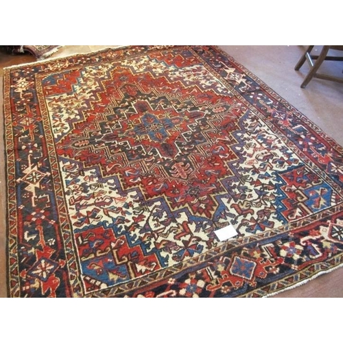 908 - North West Persian Heriz carpet central large motif fanning out on a red ground with blue, white and... 