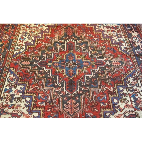 908 - North West Persian Heriz carpet central large motif fanning out on a red ground with blue, white and... 