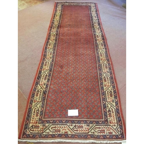 913 - North East Persian Mir runner central small repeat pattern on red ground, with a wide border and in ... 