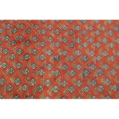 913 - North East Persian Mir runner central small repeat pattern on red ground, with a wide border and in ... 