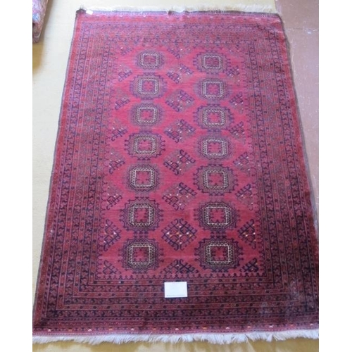 914 - A 20th century Afghan rug with repeat central motifs on deep red ground and wide border, some slight... 