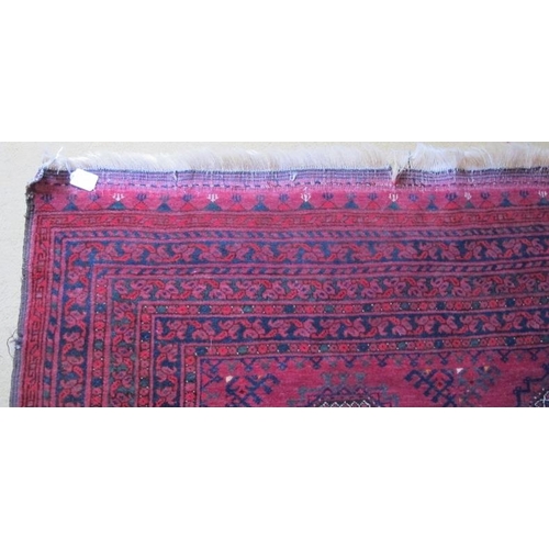 914 - A 20th century Afghan rug with repeat central motifs on deep red ground and wide border, some slight... 