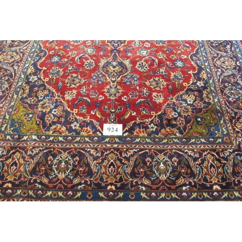 924 - A Persian Kashan carpet, central motif on a heavy patterned red ground. Good clean condition. 305cm ... 