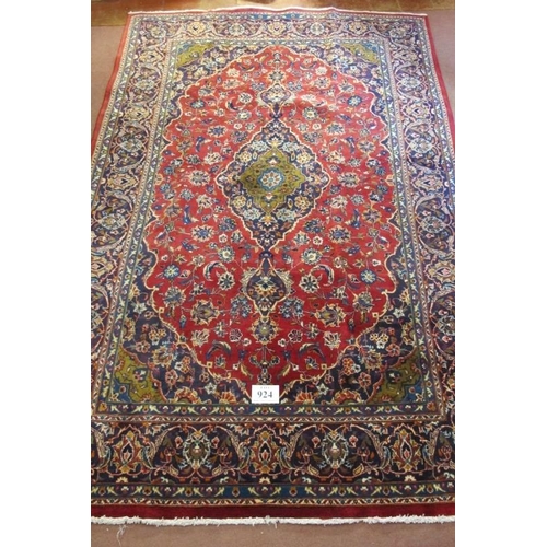 924 - A Persian Kashan carpet, central motif on a heavy patterned red ground. Good clean condition. 305cm ... 