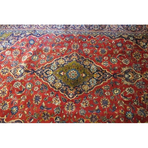 924 - A Persian Kashan carpet, central motif on a heavy patterned red ground. Good clean condition. 305cm ... 