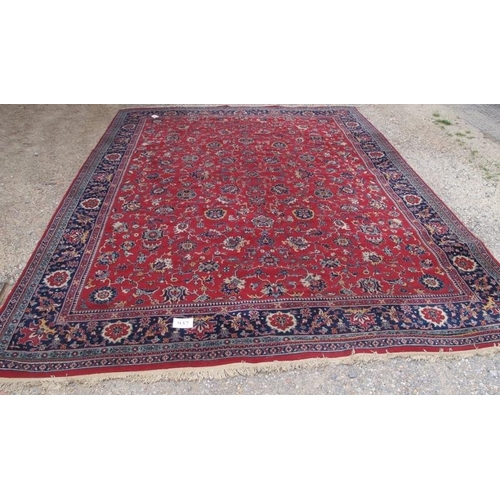 937 - A large mid 20th century Persian carpet, floral pattern on a red ground with deep blue on red border... 