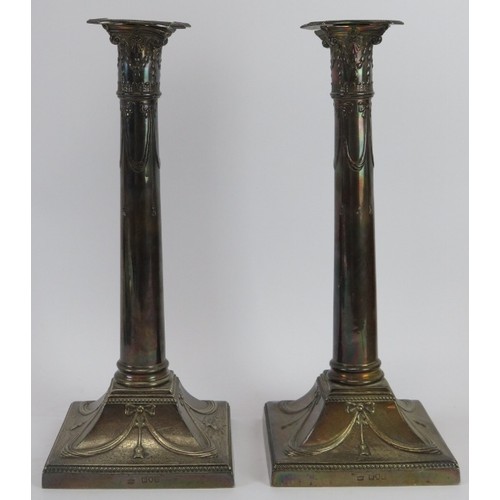 372 - A pair of Art Nouveau silver candlesticks on square bases and decorated with bows and swags. Approx ... 