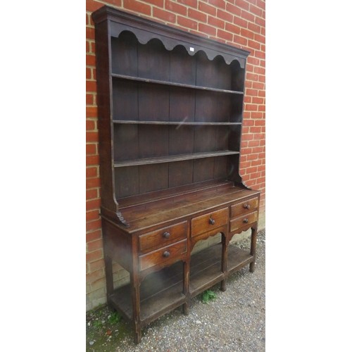 755 - An 18th century oak Welsh dresser, the top with arcaded canopy above three open shelves, the base ho... 