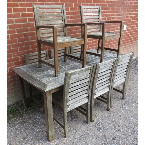 890A - A weathered teak rectangular outdoor table, together with eight (6+2) matching chairs, on square sup... 