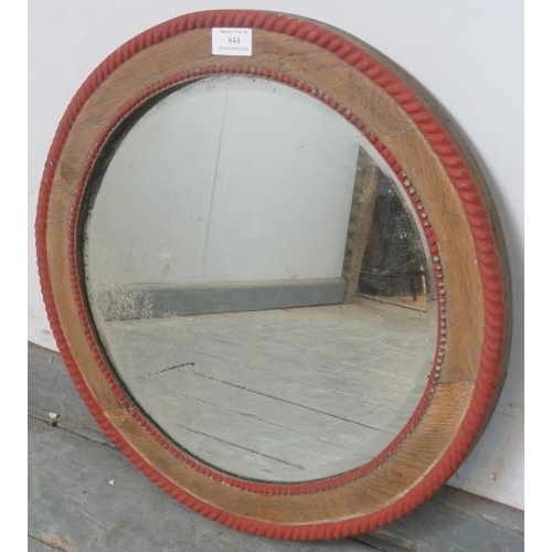 844 - A turn of the century circular bevelled wall mirror, within a stripped oak frame with beaded red acc... 
