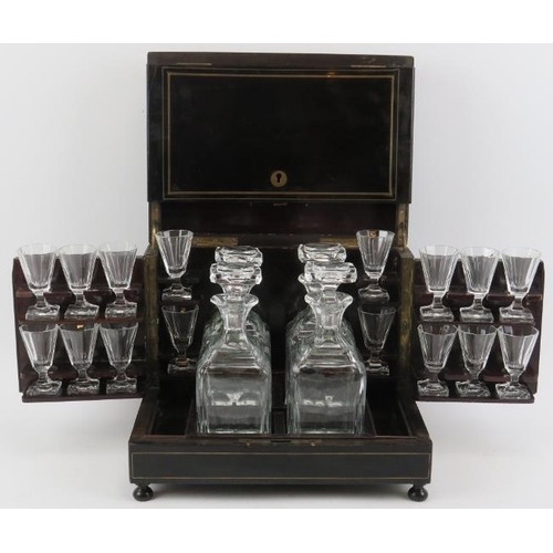 125 - An ebonised wood tantalus drinks decanter box with glassware, 19th century. With brass strung decora... 