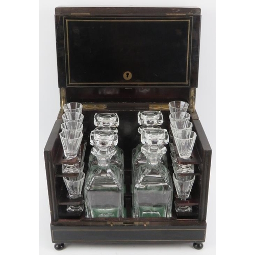 125 - An ebonised wood tantalus drinks decanter box with glassware, 19th century. With brass strung decora... 