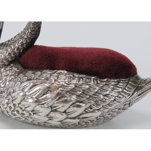 148 - An Edwardian embossed silver swan pin cushion, 20th century. With a red velvet cushion and the blue ... 