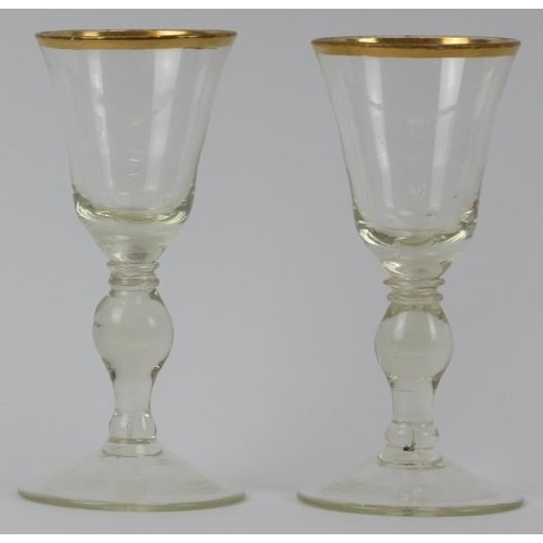 30 - A pair of European glass wine glasses, probably early 19th century. Both with gilt rims and knopped ... 