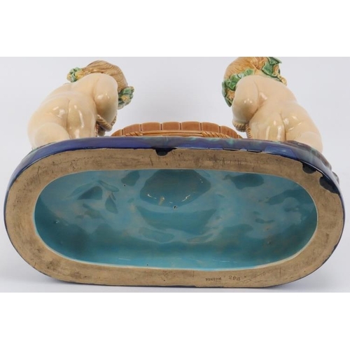 50 - A Minton majolica comport modelled depicting two putti tub basket carriers, 19th century. Impressed ... 