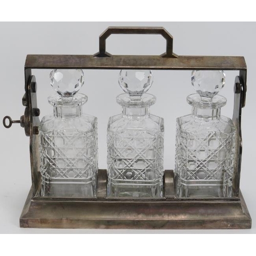 82 - An English silver plated tantalus with three hobnail pattern decorated glass decanters, early 20th c... 