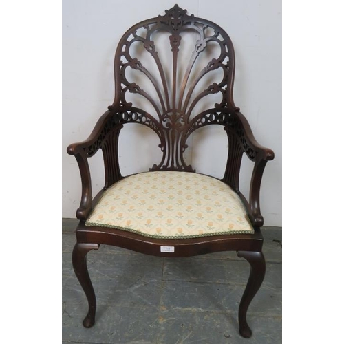 719 - An Edwardian mahogany open sided armchair, having a very ornately carved and pierced back, the seat ... 