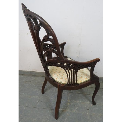 719 - An Edwardian mahogany open sided armchair, having a very ornately carved and pierced back, the seat ... 