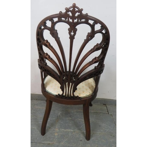 719 - An Edwardian mahogany open sided armchair, having a very ornately carved and pierced back, the seat ... 