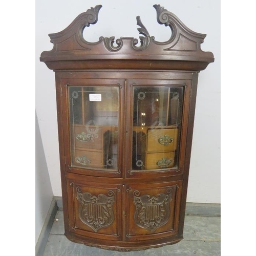 735 - An Edwardian ornately carved mahogany bow front hanging wall cabinet, shaped pediment above etched g... 