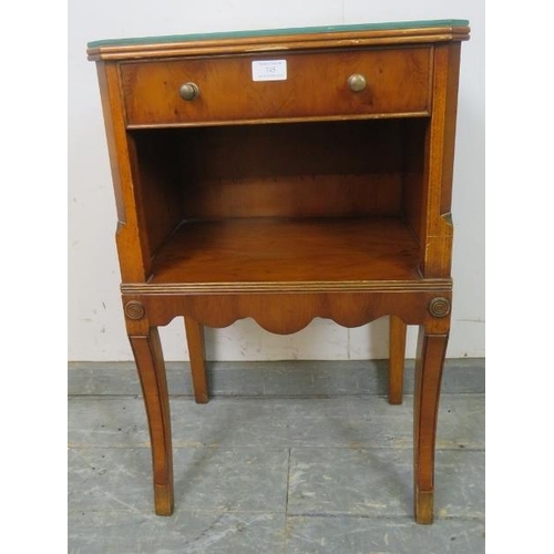 745 - A reproduction yew wood bedside cabinet, housing one long cock-beaded drawer with brass handles, abo... 