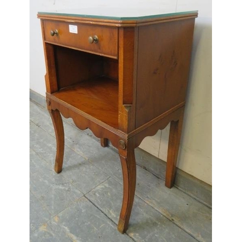 745 - A reproduction yew wood bedside cabinet, housing one long cock-beaded drawer with brass handles, abo... 