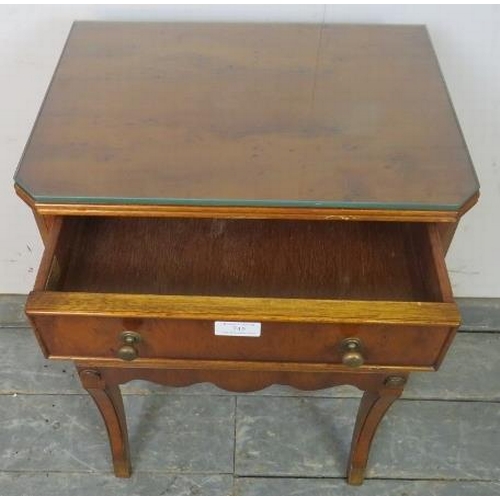 745 - A reproduction yew wood bedside cabinet, housing one long cock-beaded drawer with brass handles, abo... 