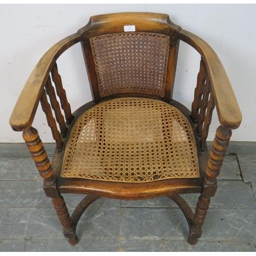 747 - An antique fruitwood Continental bergère tub chair, the curved arms joined by shaped spindles and ba... 