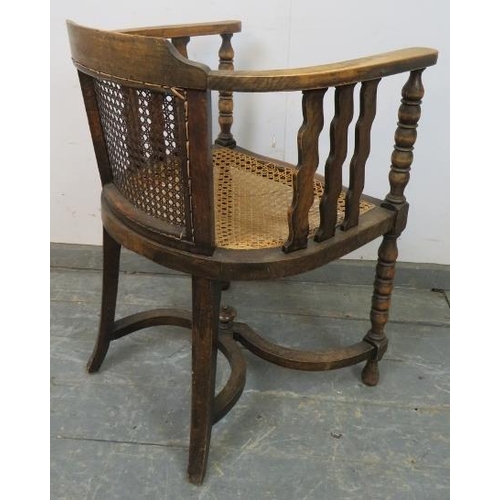 747 - An antique fruitwood Continental bergère tub chair, the curved arms joined by shaped spindles and ba... 