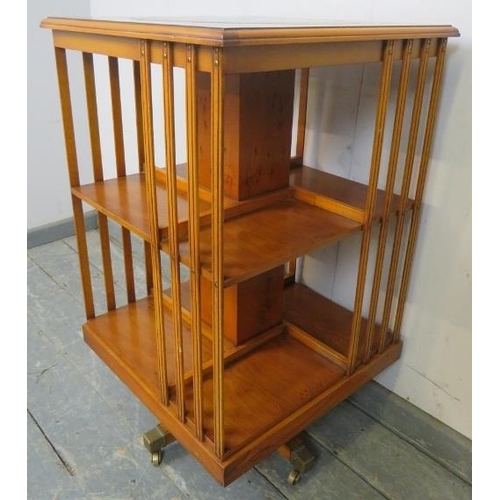 753 - A reproduction cross-banded yew wood revolving book table, with inset gilt tooled green leather top.... 