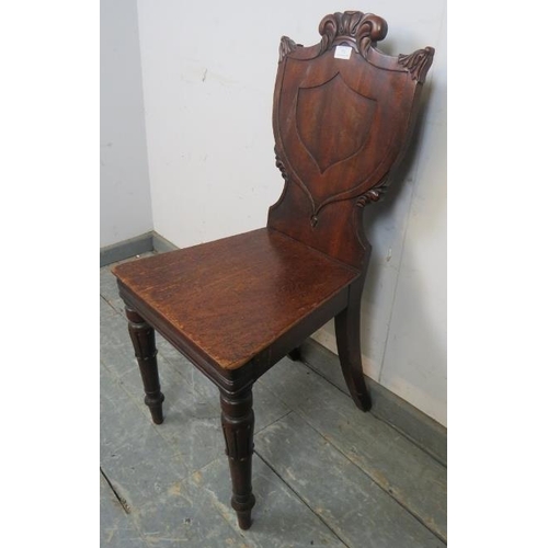 771 - A 19th century mahogany hall chair, the shield back with acanthus carved details, on tulip carved ta... 