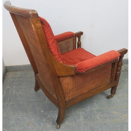 827 - A 19th century mahogany and bergère library chair, with loose cushions upholstered in crimson chenil... 