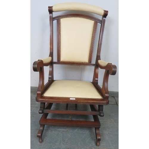 864 - An early 20th century American mahogany ‘Dexter’ rocking chair, re-upholstered in cream leather with... 