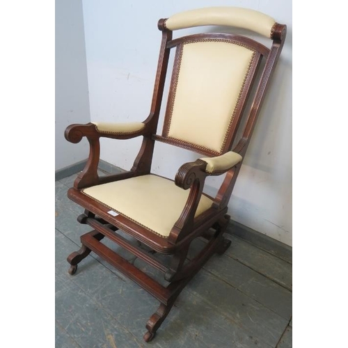 864 - An early 20th century American mahogany ‘Dexter’ rocking chair, re-upholstered in cream leather with... 