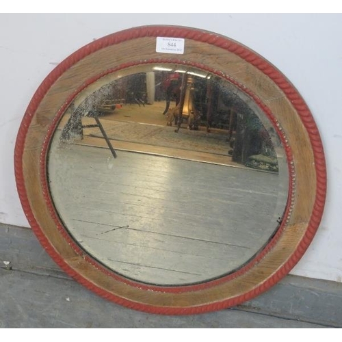 875 - A turn of the century circular bevelled wall mirror, within a stripped oak frame with beaded red acc... 