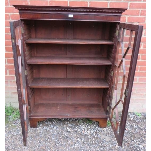 883 - A George III mahogany enclosed bookcase, having a dentil cornice above astral glazed doors, opening ... 