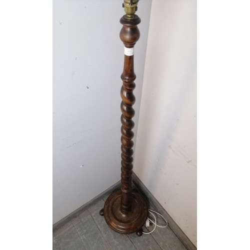 832 - An antique mahogany standard lamp, the tapering barley twist column on a dished circular plinth base... 