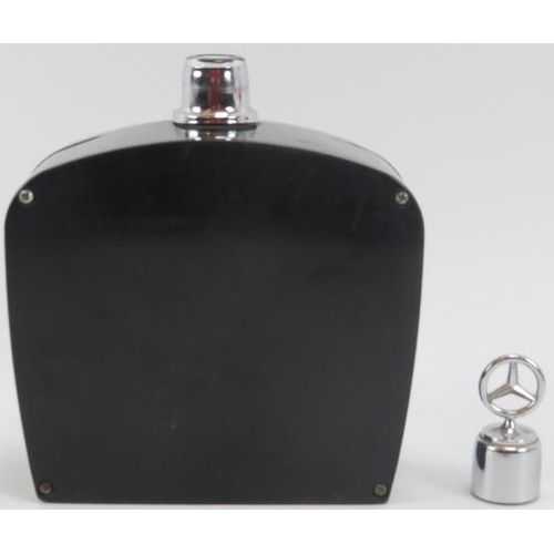 254 - Automobilia: A vintage Mercedes Benz car grill drinks decanter flask and two car bonnet emblems, mid... 