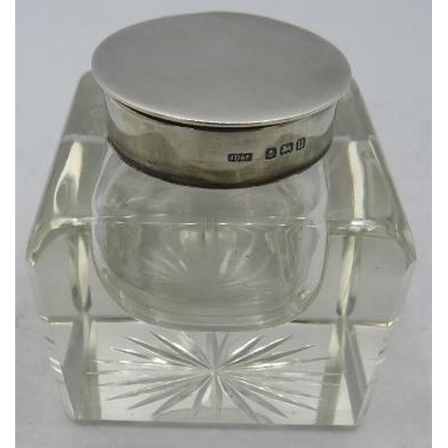 375 - A heavy square glass inkwell with star cut base, silver hinged lid, sitting in a silver galleried sq... 